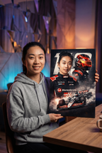 Person holding a canvas portrait of her as a F1 racing driver from Haas F1 team